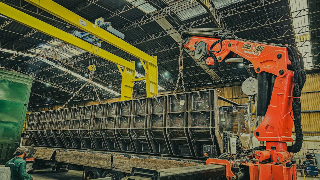 A large crane is used to load a container onto a truck inside a warehouse.