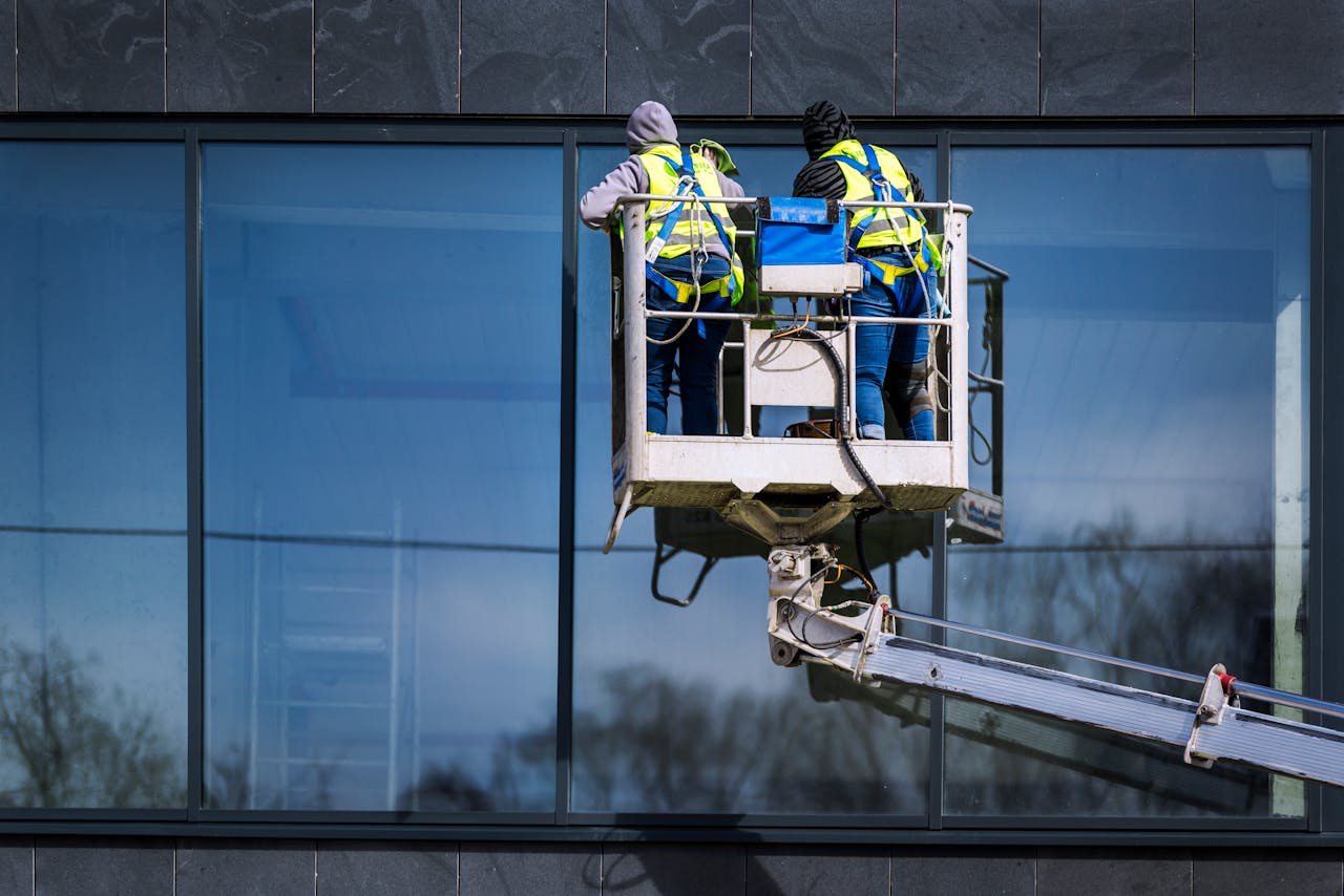 The Art of Drawing Readers In: Your attractive post title goes here Two men on a hydraulic lift cleaning windows of a modern skyscraper. Urban reflection visible in the glass.