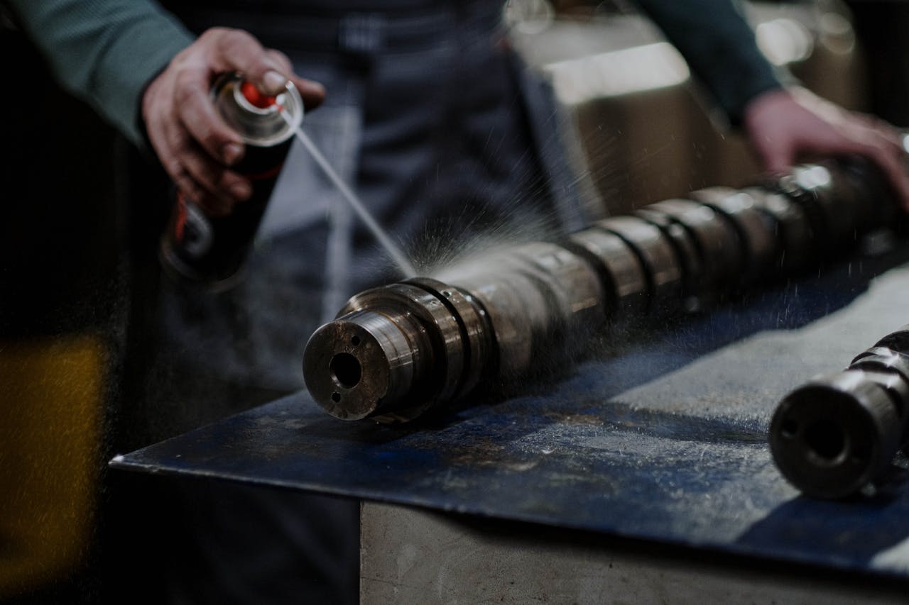 Crafting Captivating Headlines: Your awesome post title goes here Mechanic meticulously sprays degreaser onto an engine camshaft for maintenance.